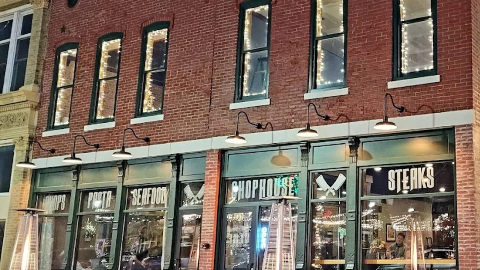 The brick facade of 1830 Chophouse lit from within at dusk