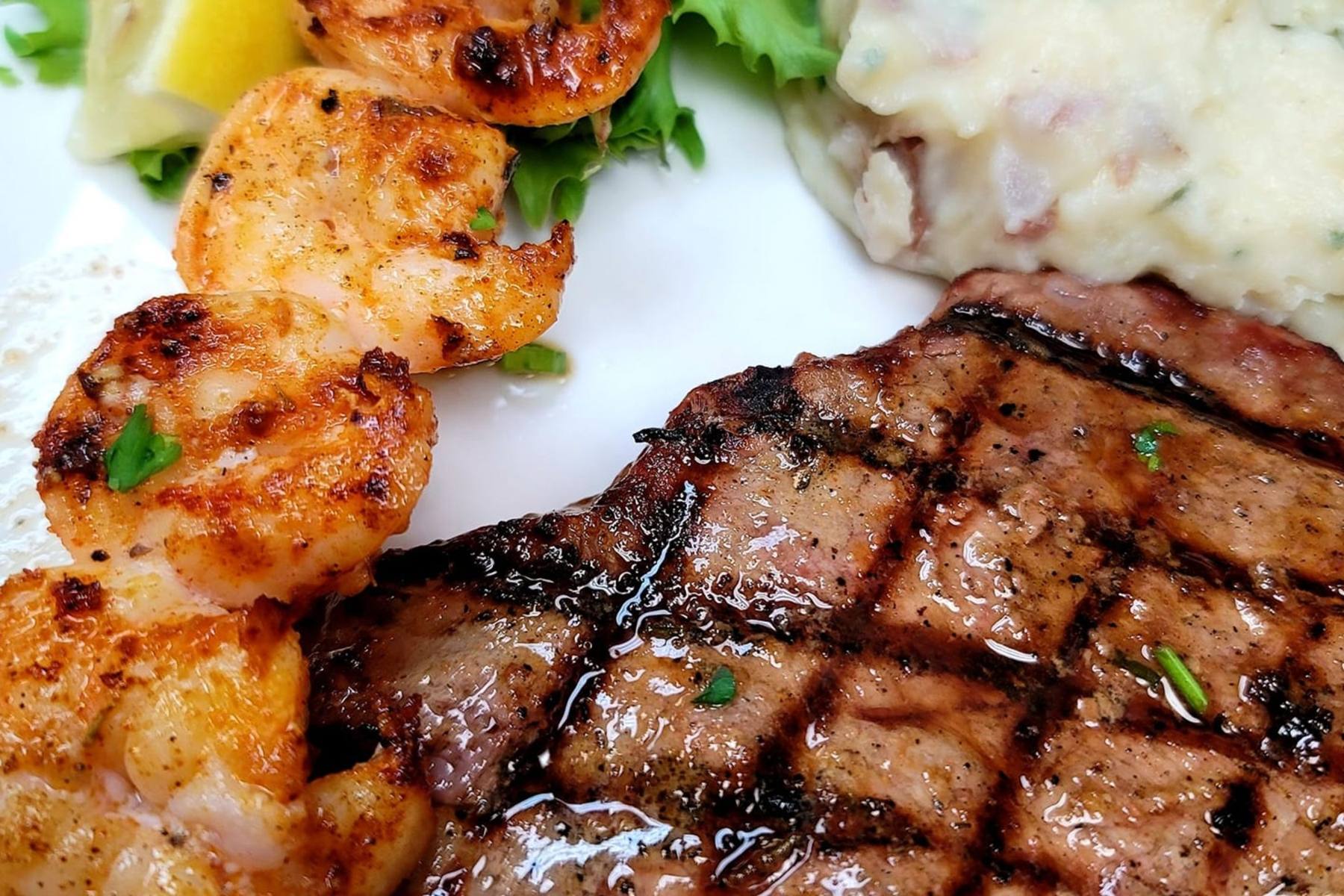 A grilled filet and jumbo shrimp plated with garlic mashed potatoes