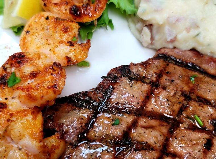 A grilled filet and jumbo shrimp plated with garlic mashed potatoes