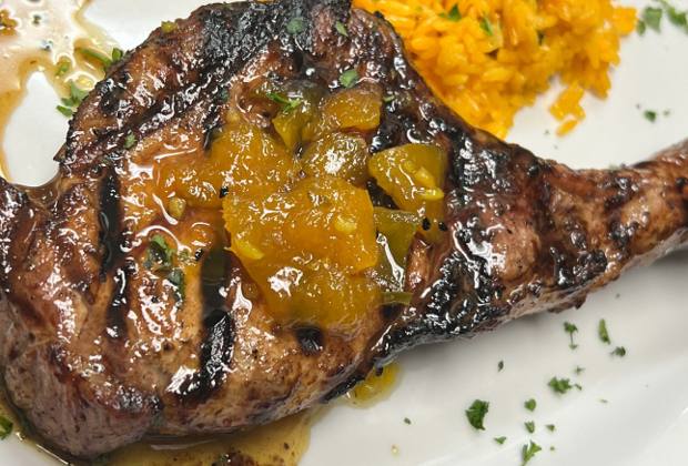 A bone-in pork chop topped with mango chutney