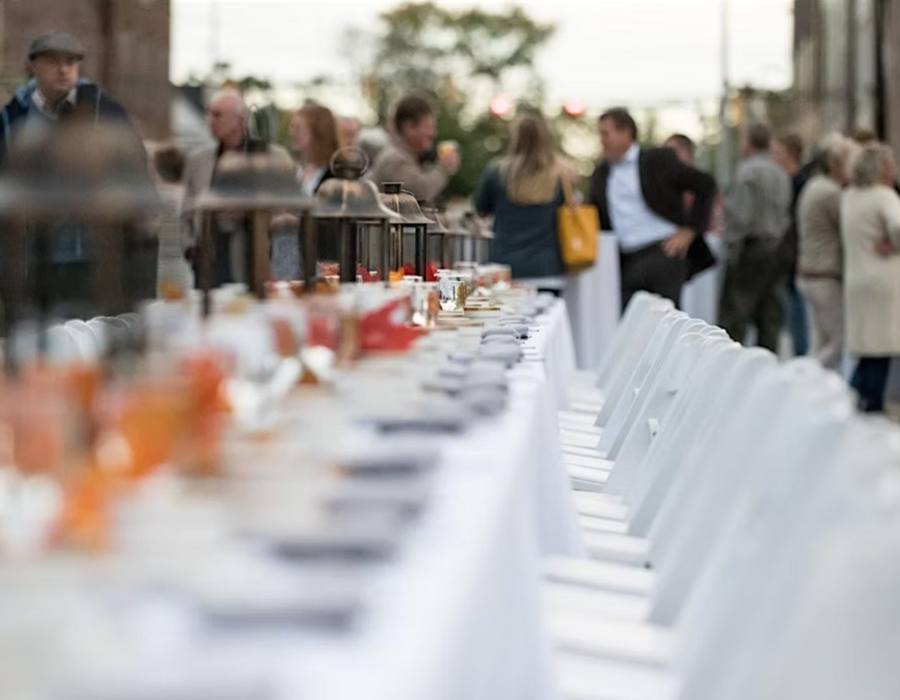 Neighbors seated at one long table down the middle of Main Street