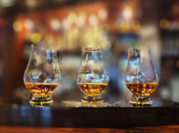 Three glasses of bourbon poured as a tasting flight on the bar